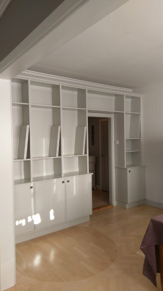 platsbyggd grå bokhylla med bänkskåp måttanpassad runt dörröppning